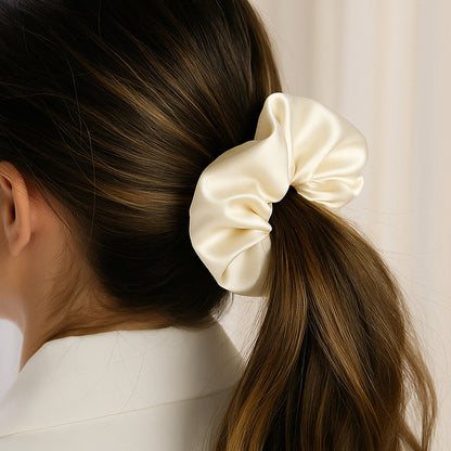 Chouchou en satin de soie crème attaché dans des cheveux bruns