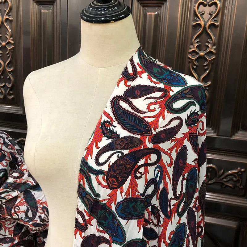 Drapé de tissu en soie de mûrier à motifs cachemire colorés sur un mannequin de couture, idéal pour la confection de robes.