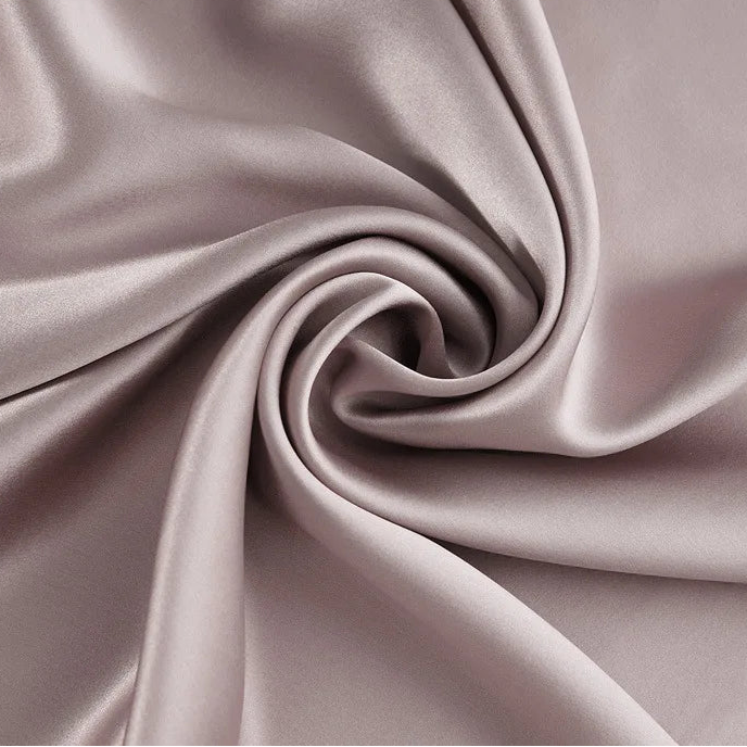 Gros plan sur un coupon de tissu en soie de mûrier de couleur rose taupe, texture satinée et fluide pour couture de luxe