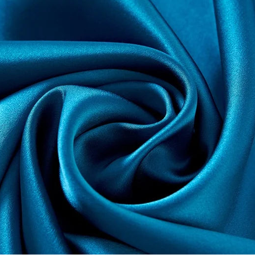Détail d'un drapé en soie de mûrier bleu canard profond avec des reflets satinés et une texture luxueuse.