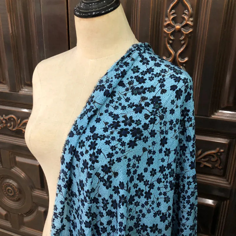 Drapé de soie de mûrier bleu ciel à motifs floraux noirs sur un mannequin de couture en bois.