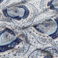 Tissu en soie de mûrier imprimé de motifs mandalas et rosaces bleu porcelaine sur fond blanc, textile fluide vendu à la coupe pour robes et foulards.