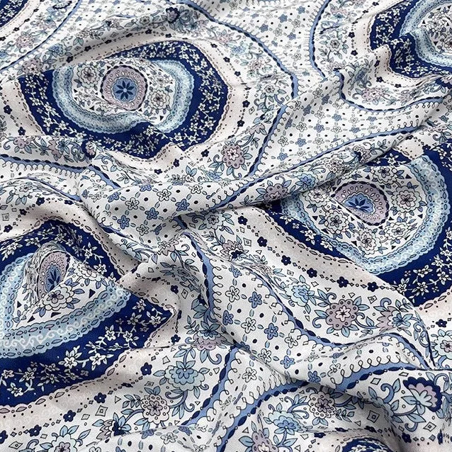 Tissu en soie de mûrier imprimé de motifs mandalas et rosaces bleu porcelaine sur fond blanc, textile fluide vendu à la coupe pour robes et foulards.
