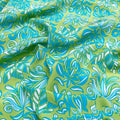 Tissu en soie de mûrier imprimé jungle aux motifs de feuilles exotiques vert anis et turquoise, soie fluide vendue à la coupe pour vêtements d'été.